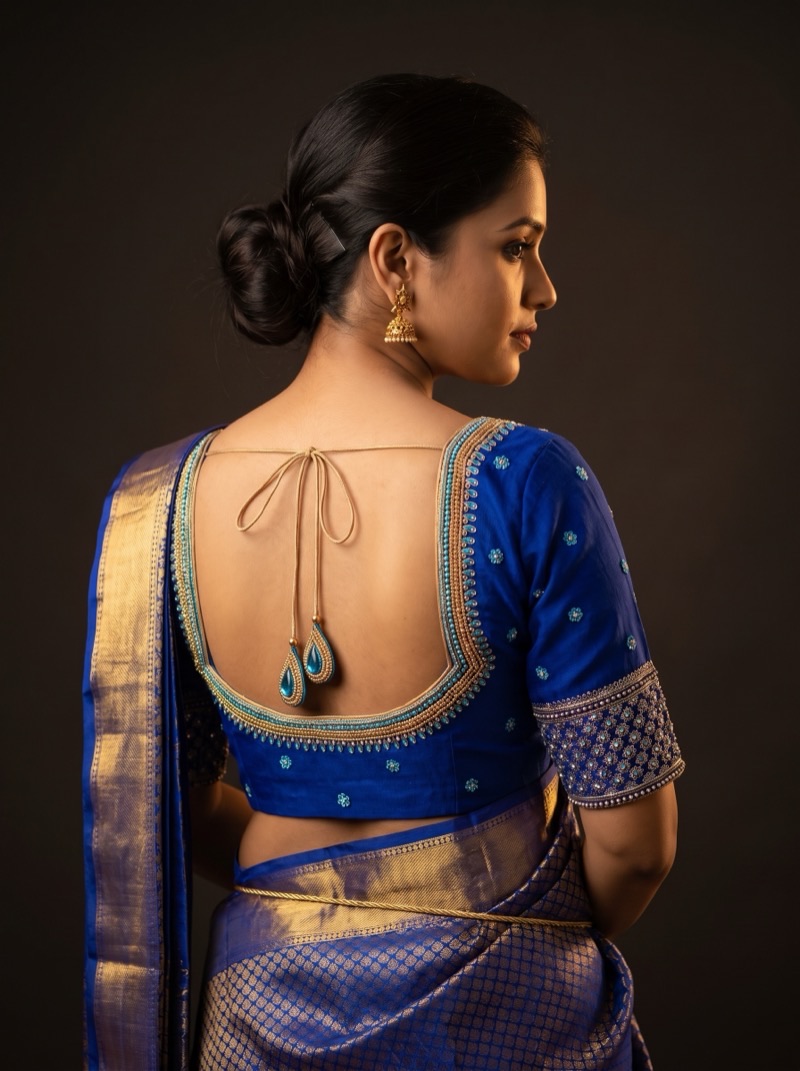 Back view of a royal blue blouse with a scalloped gold bead border and turquoise teardrop beads.